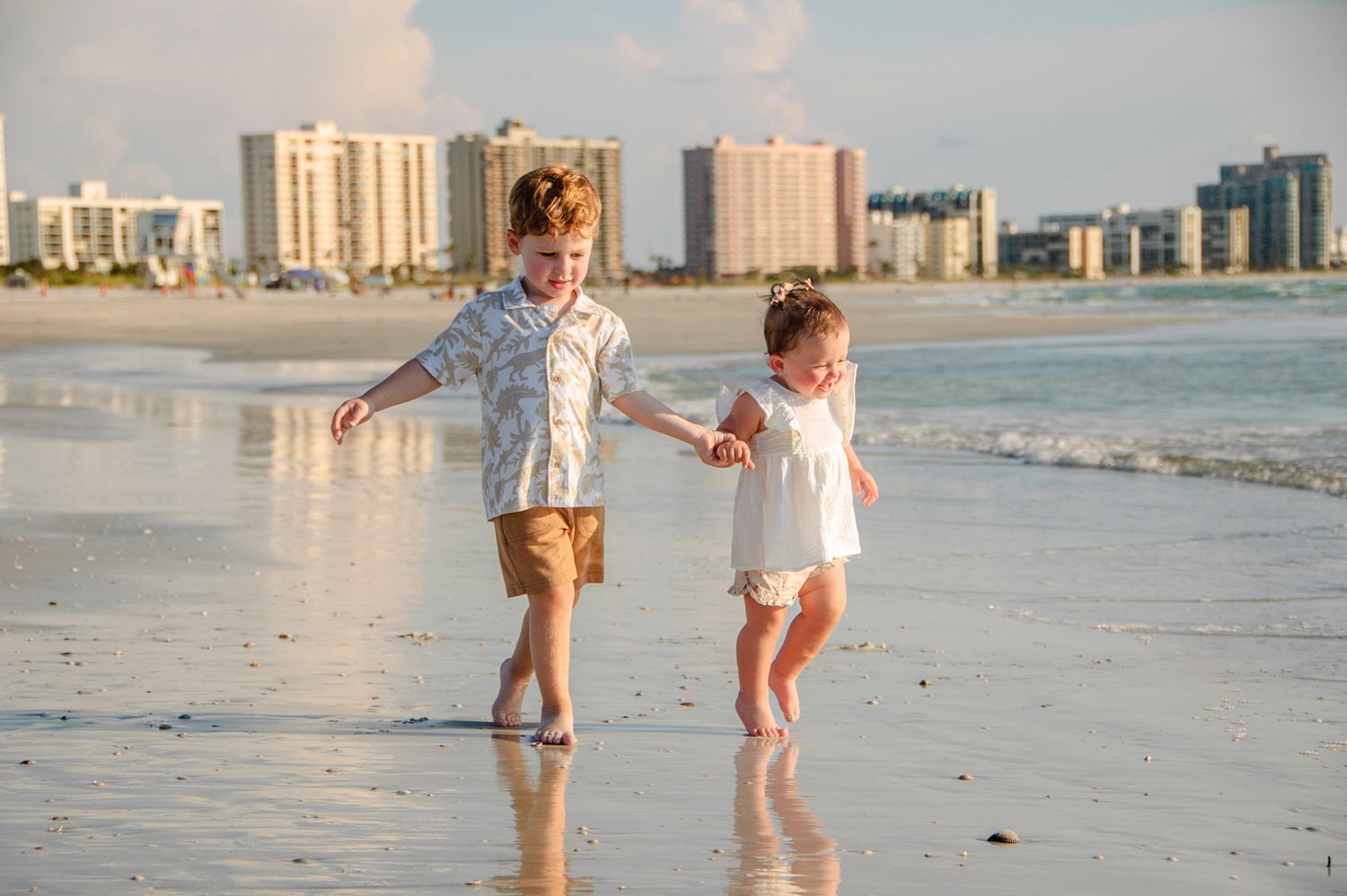photo of young brother and sister walking on beach in New Port Richey