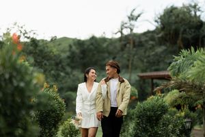 Couple sharing intimate moments while walking through a lush garden setting.