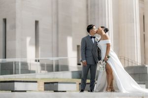 Elegant wedding couple poses against classic stone column architecture.