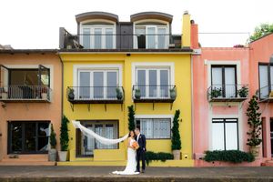 Colorful modern apartment buildings with balconies and windows in pastel yellow, pink and orange tones.