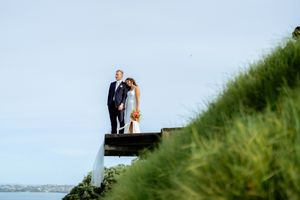 Romantic wedding photos taken on a grassy hillside overlooking water.