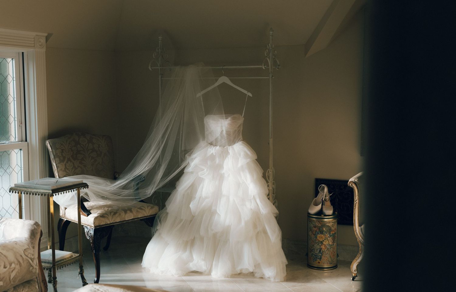 A bride in flowing dress walks across a lawn with string lights overhead.