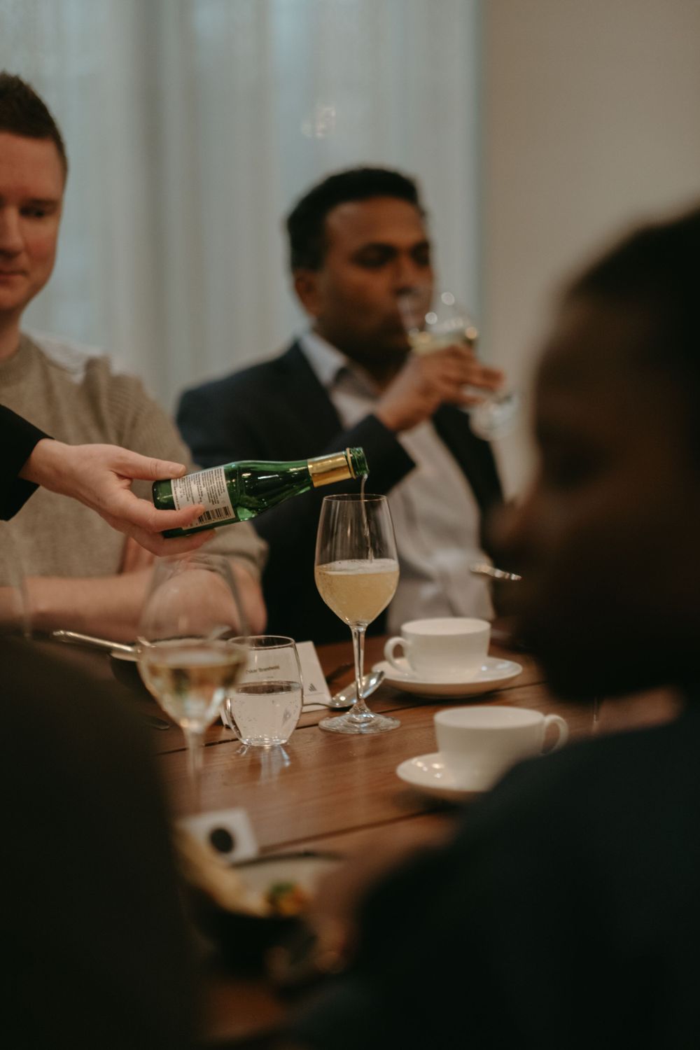 detail of a waitress pouring wine into a wine glass during lunch event while being captured by Stockholm event photographer