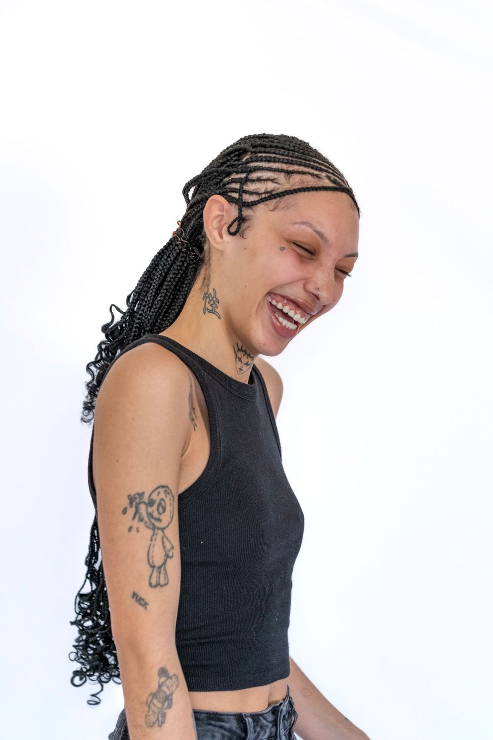 Candid portrait showing joyful laughter and braided hairstyle against white backdrop.