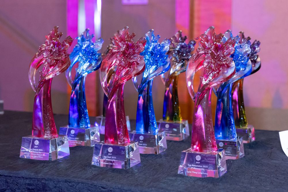 A row of blue and pink translucent crystal trophies arranged on a dark surface with colorful lighting effects.