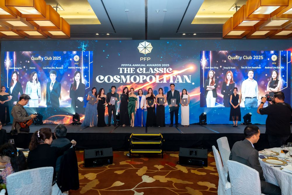 Award recipients stand on stage at a formal business ceremony with blue backlit banners and elegant lighting.