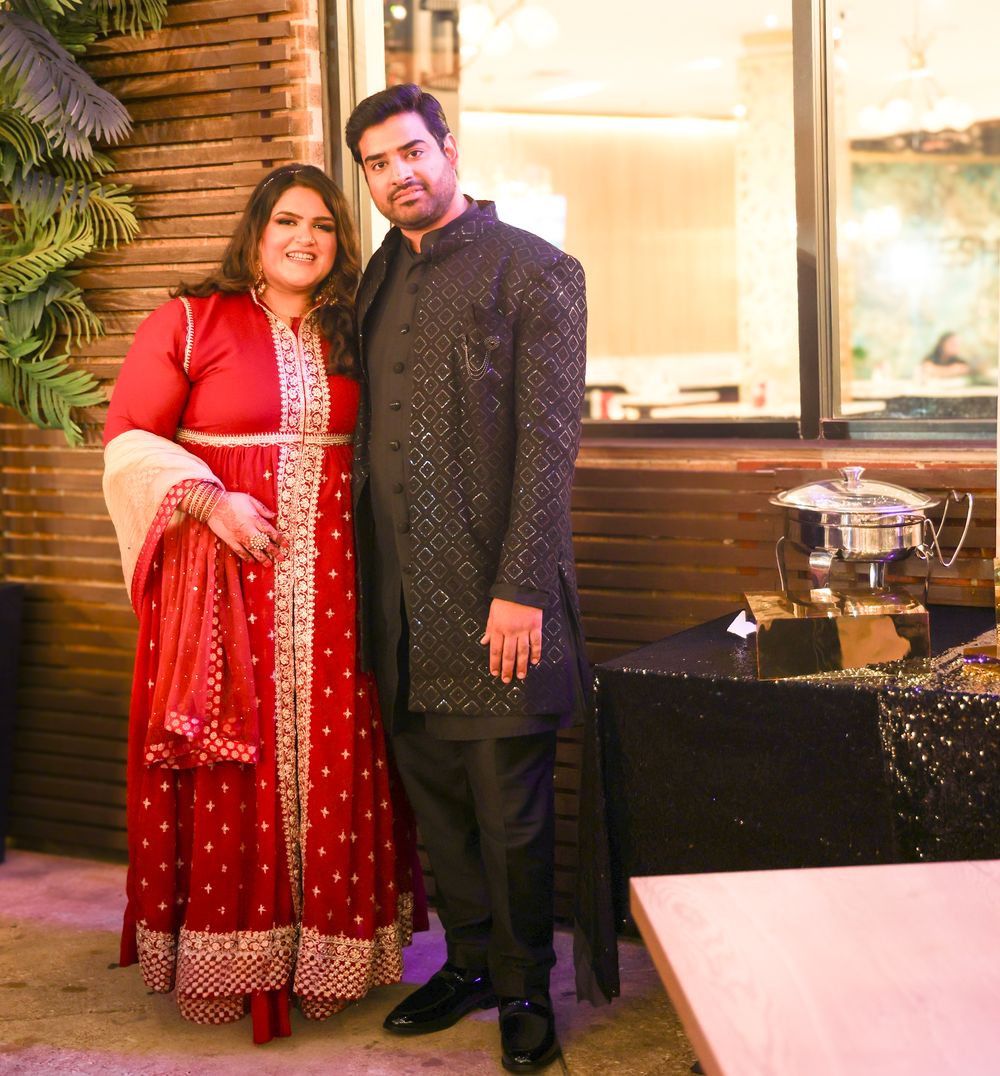 A couple in traditional Indian formal wear poses at an elegant venue.