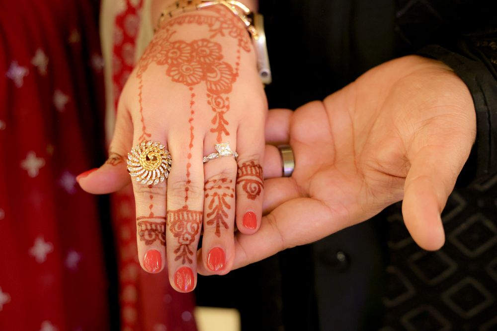 Close-up shots of hands adorned with intricate henna designs and jewelry at a traditional celebration.