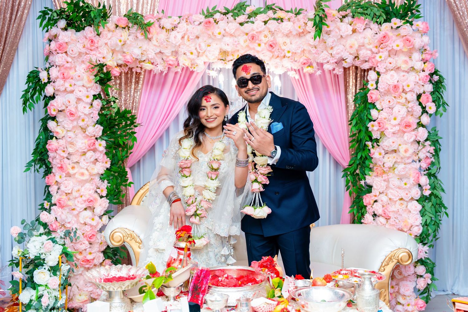 Celebratory scene with floral arch backdrop featuring pink roses and white flowers.