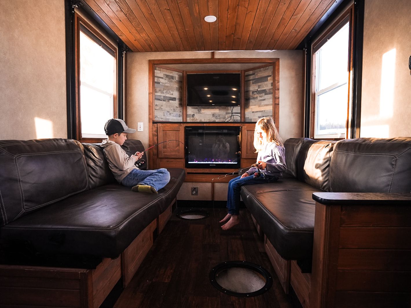 Rustic RV living room with leather couches and stone fireplace.