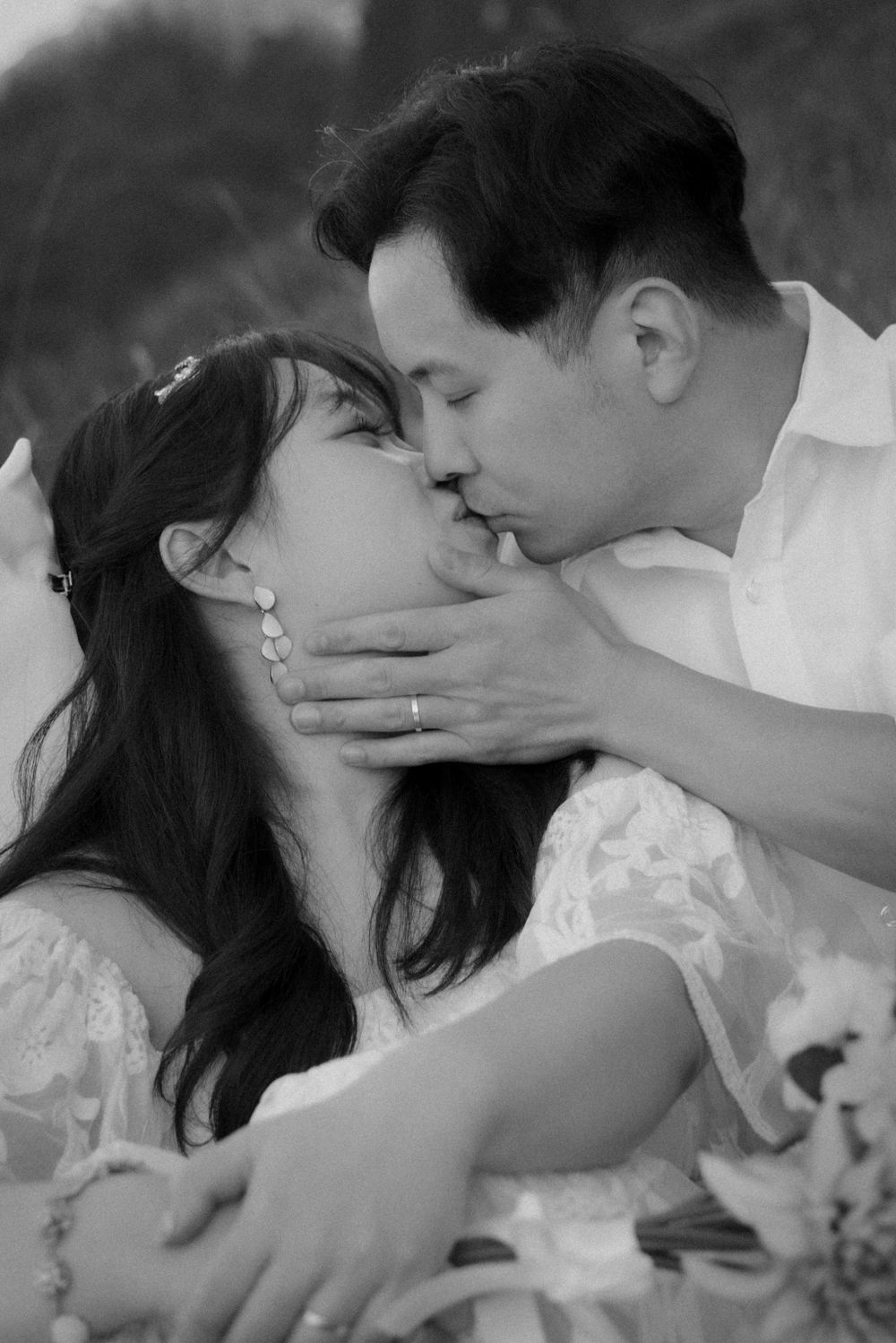 An intimate black and white portrait of newlyweds sharing a passionate kiss.