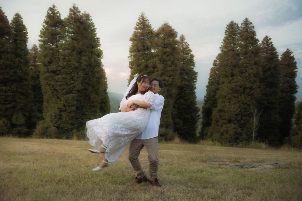 A romantic couple enjoys a playful moment together in a scenic mountain meadow at sunset.