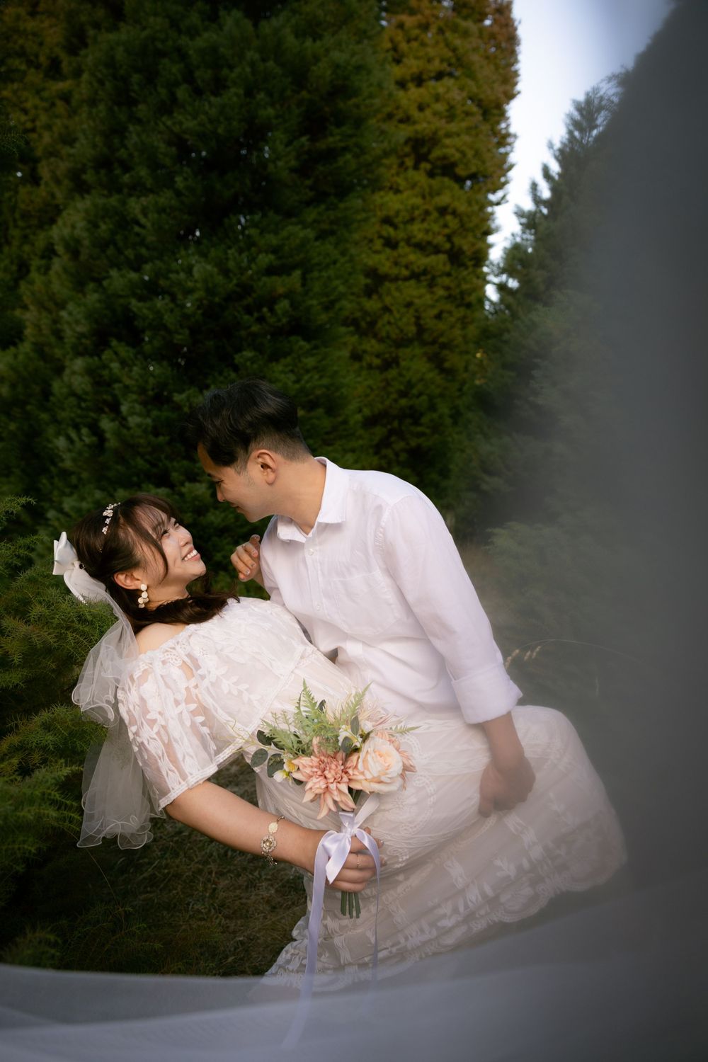 A romantic photoshoot in a mountain meadow with blooming flowers and evergreen trees.