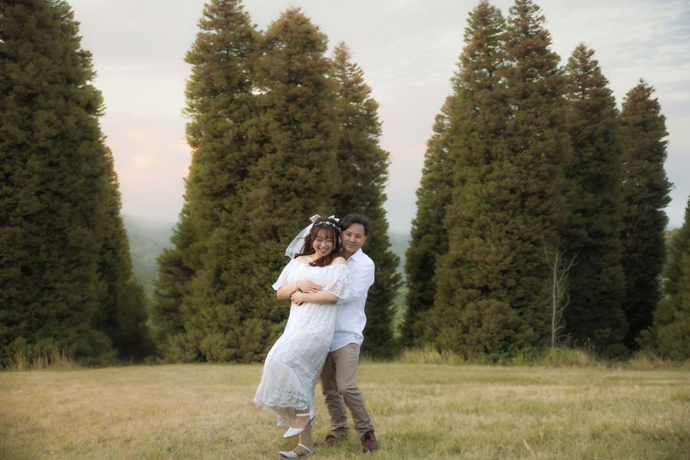 A wedding couple dances and poses playfully in a scenic mountain meadow.