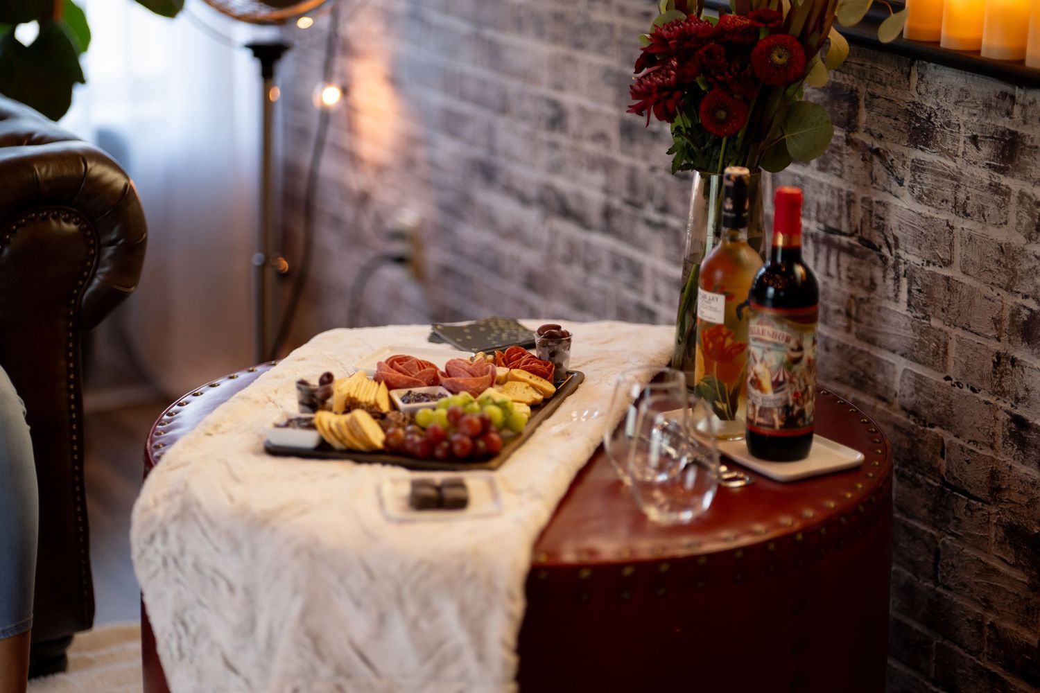 Elegant charcuterie board and wine setup against exposed brick wall.