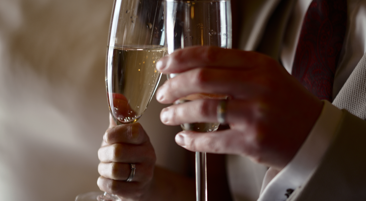 A hand holding a champagne flute filled with sparkling wine against a blurred background.
