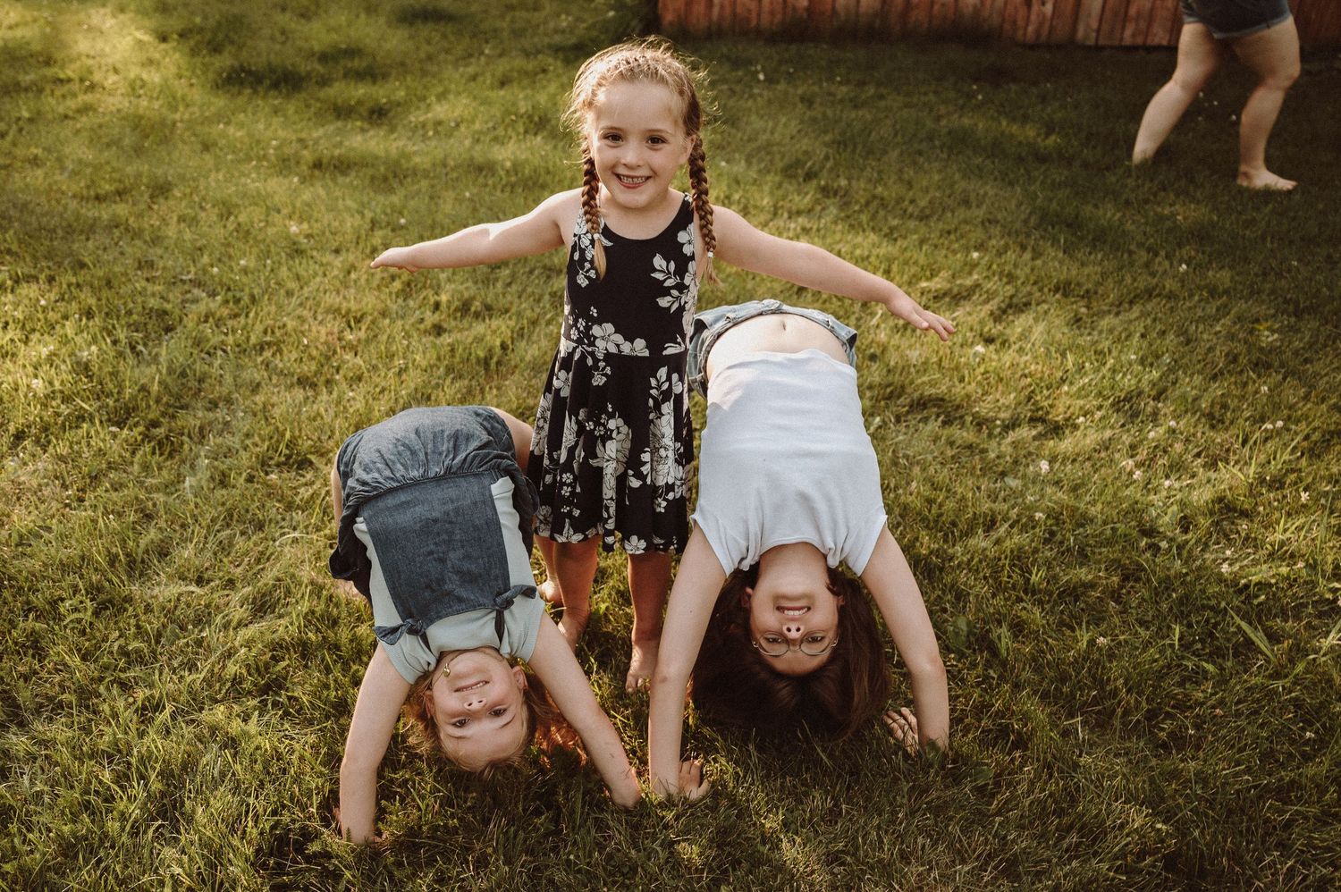 Children playing and doing handstands on grass.