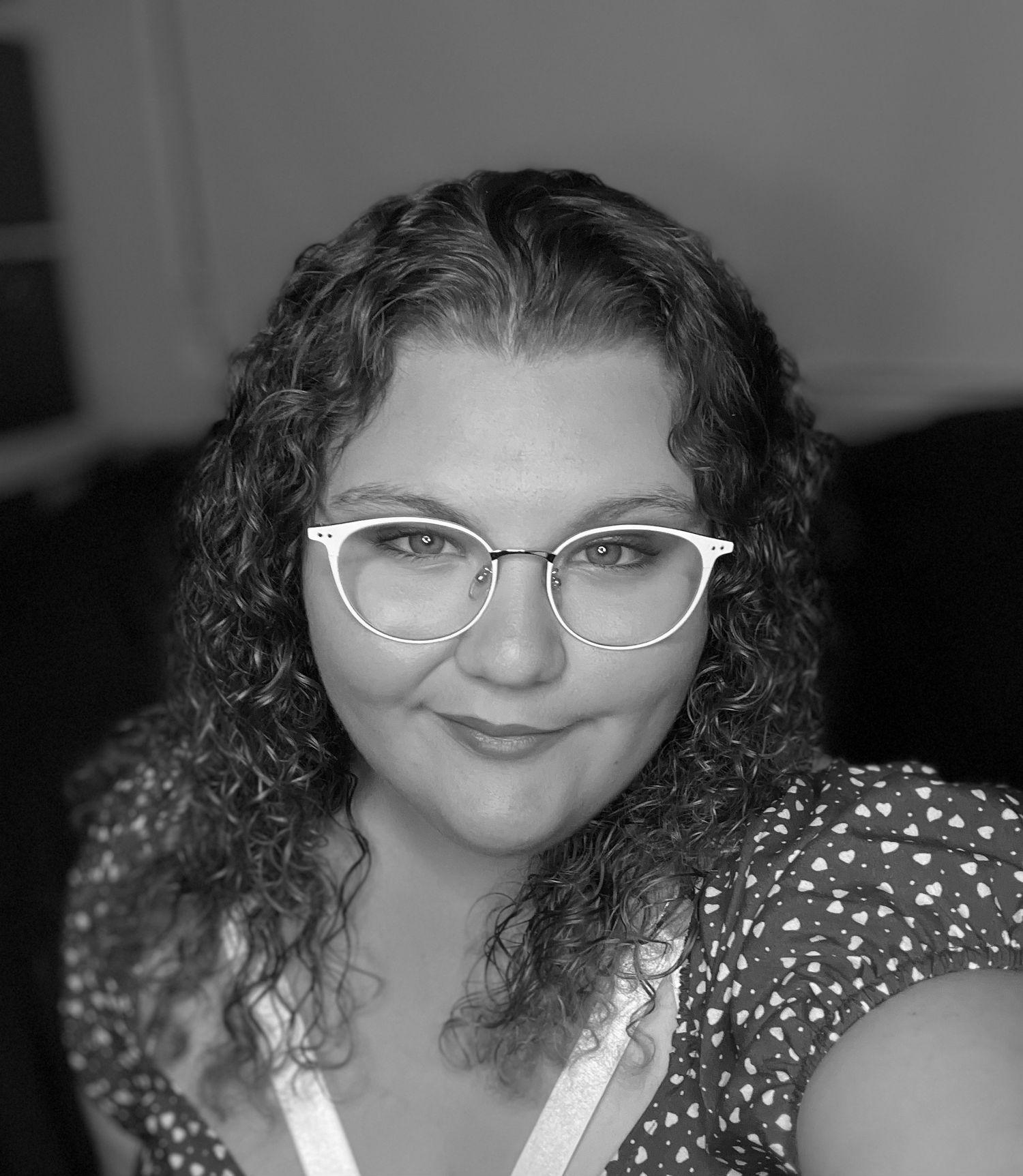 Black and white portrait featuring white cat-eye glasses and curly hair.