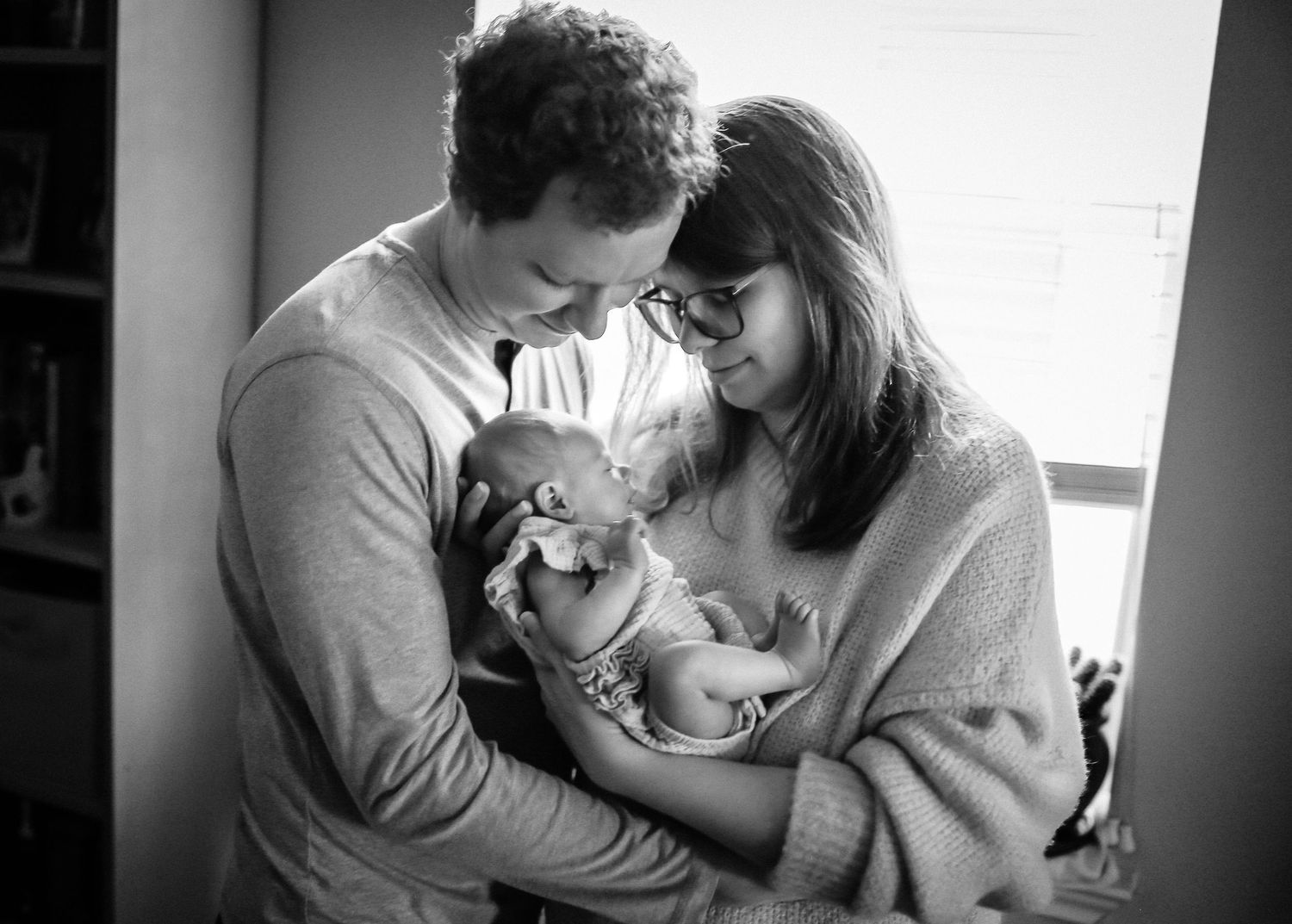 Mother and father staring at baby girl while doing In-home lifestyle session