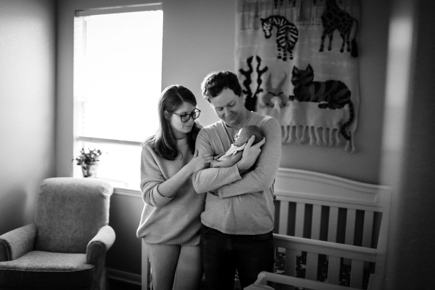 In newborns nursery while mom and dad look at baby girl