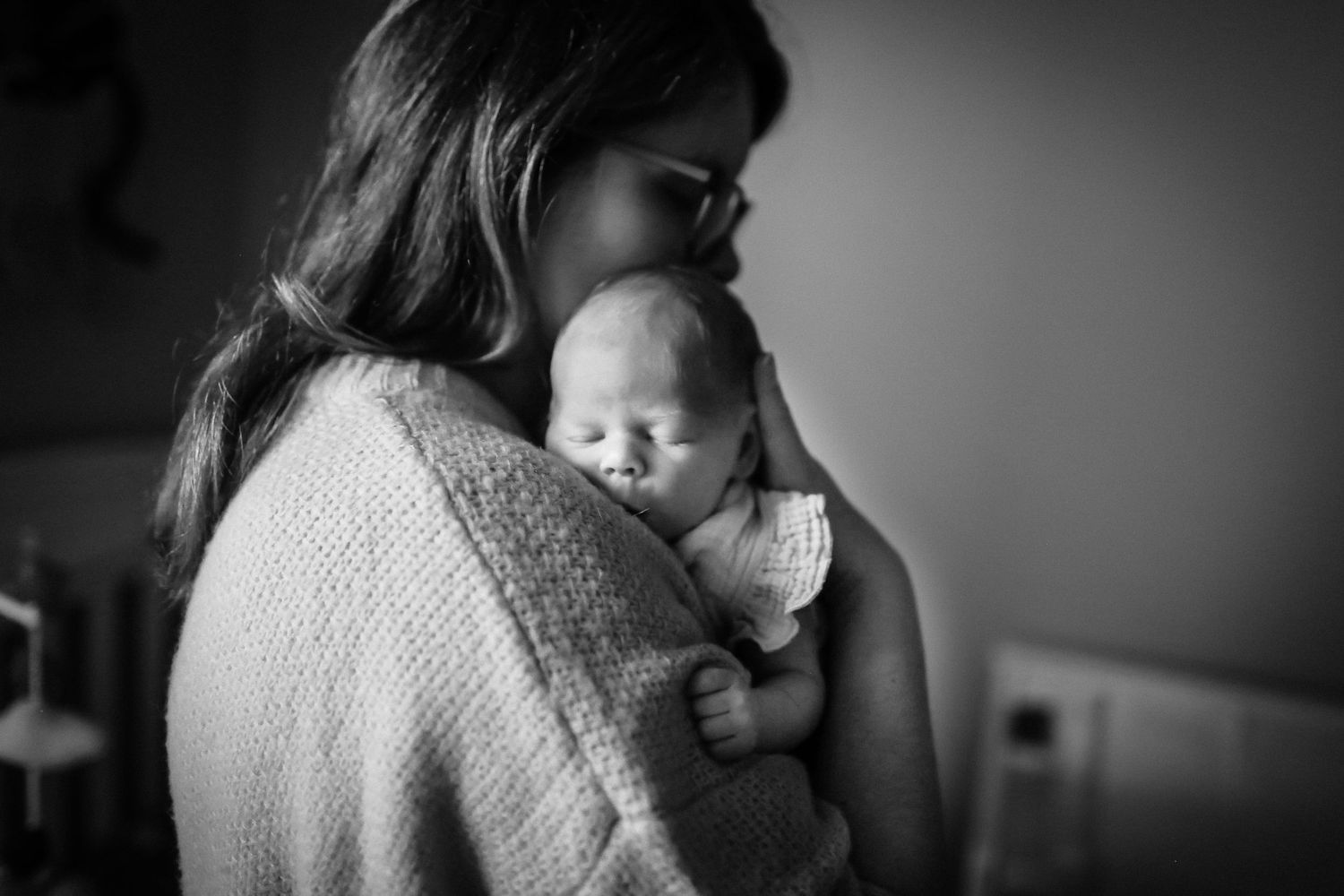 Mommy snuggling newborn daughter on her shoulder
