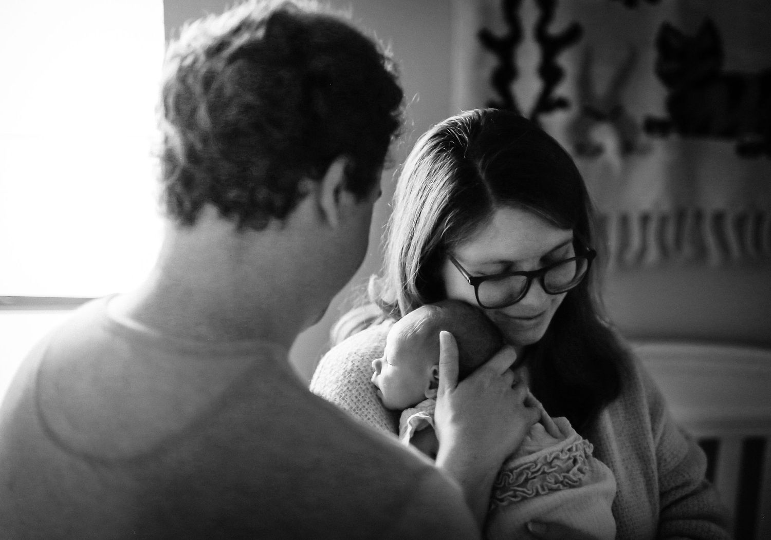 In-home lifestyle session  while daddy stares at mama and daughter