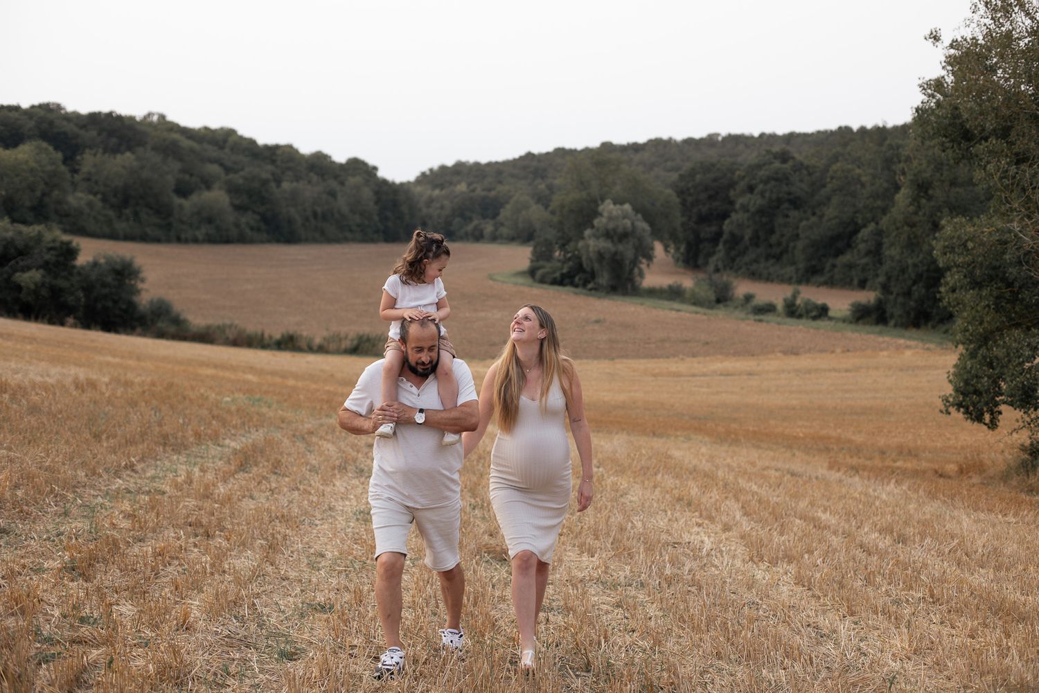 famille complice séance grossesse dans les champs
