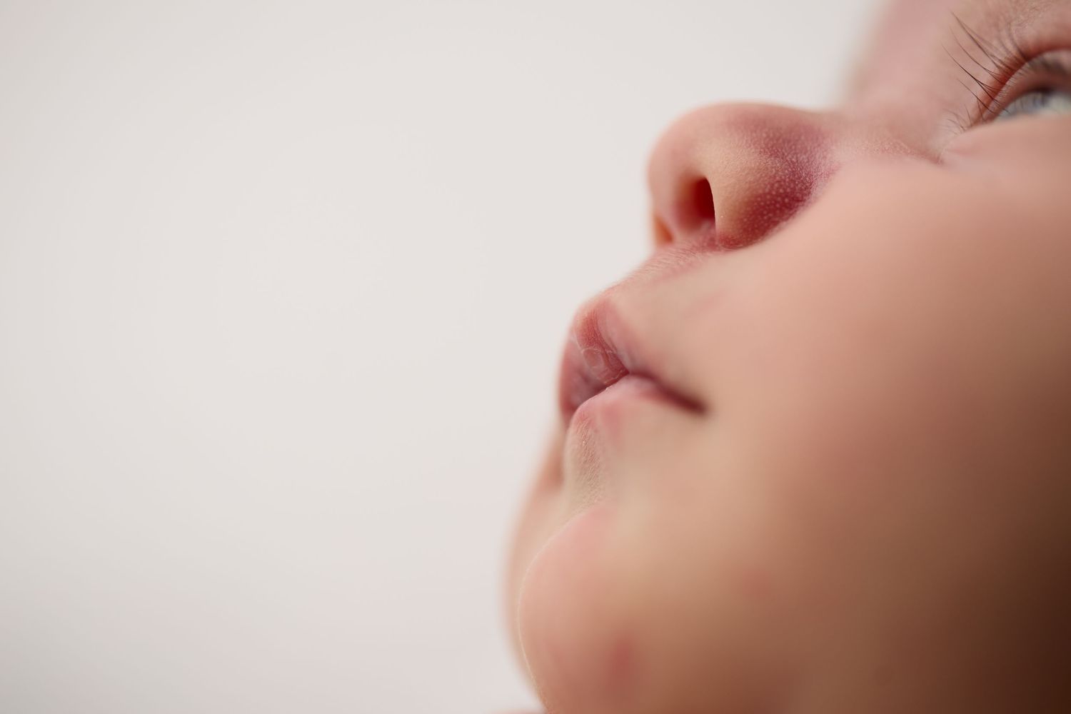 Close-up profile view of rosy lips and nose against soft white background.