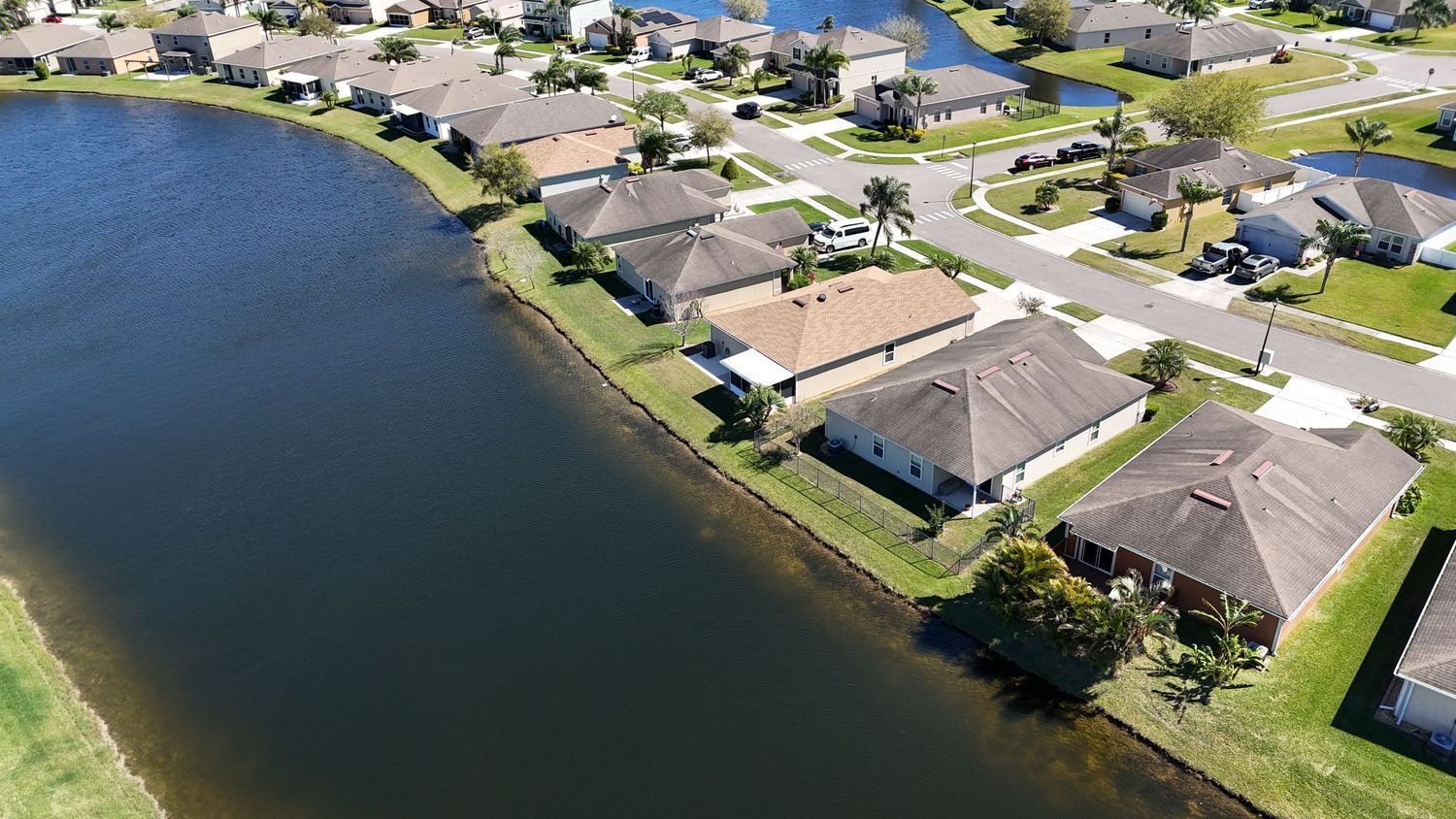 Drone shot of waterfront properties with private docks along a curved shoreline.