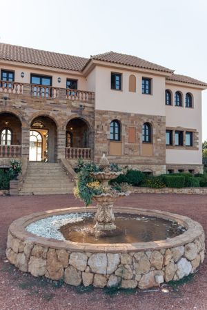 Mediterranean-style villa with stone fountain and arched entryway.