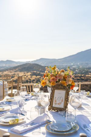 Elegant outdoor wedding table setting with floral centerpiece overlooking mountain vista.
