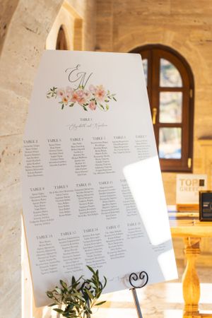 Wedding seating chart with floral design and elegant monogram displayed on easel.