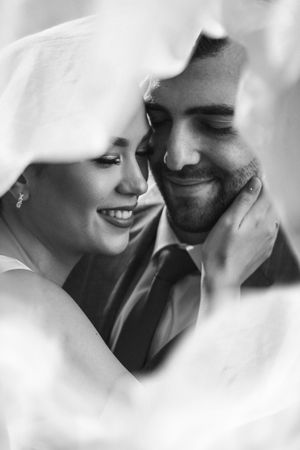 Intimate black and white portrait of couple sharing romantic moment under veil. Next day wedding photography.