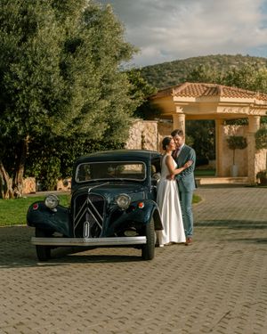 Classic vintage car parked in front of Mediterranean style architecture with a couple in wedding attire. Next day wedding photography.