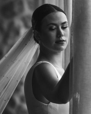 Black and white portrait of a bride in a sleeveless dress and veil looking to the side. Next day wedding photography.