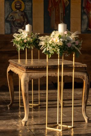 Elegant floral arrangements with white candles on gold stands atop vintage table.