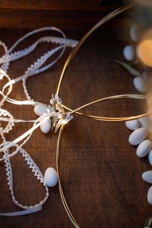 White and gold wedding accessories arranged on dark wooden surface with ambient lighting.