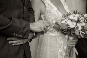 Black and white photo capturing hands during an intimate wedding moment.