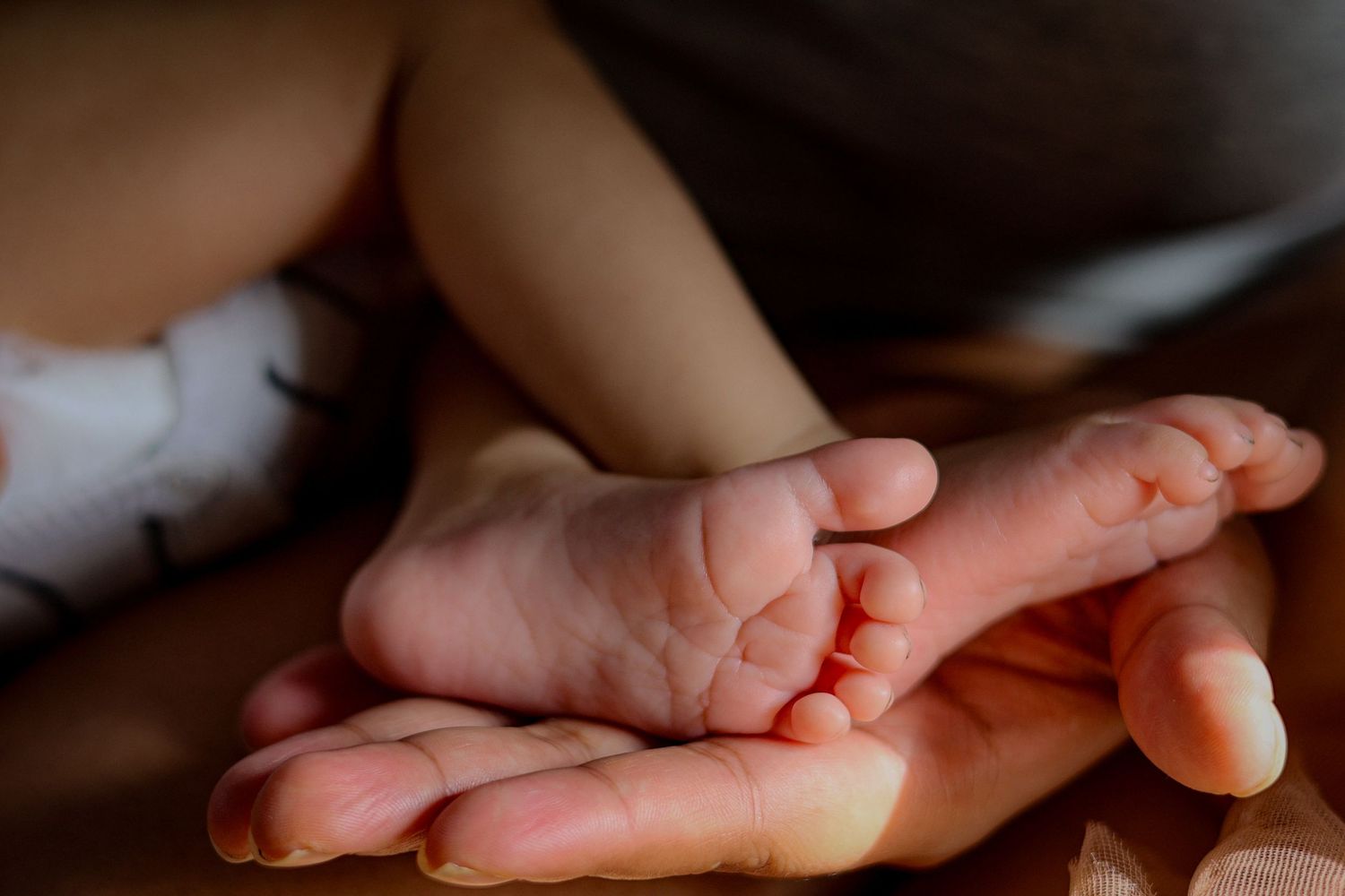 newborns feet held in mums hand detailing colour, newborn natural light