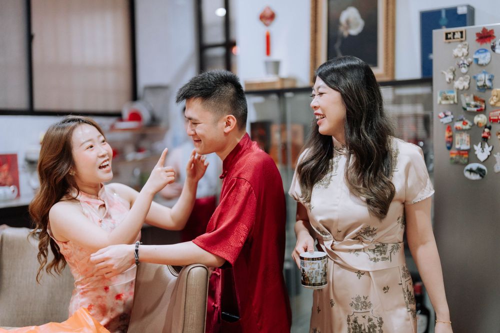 Three people in traditional Chinese attire sharing a joyful moment indoors.