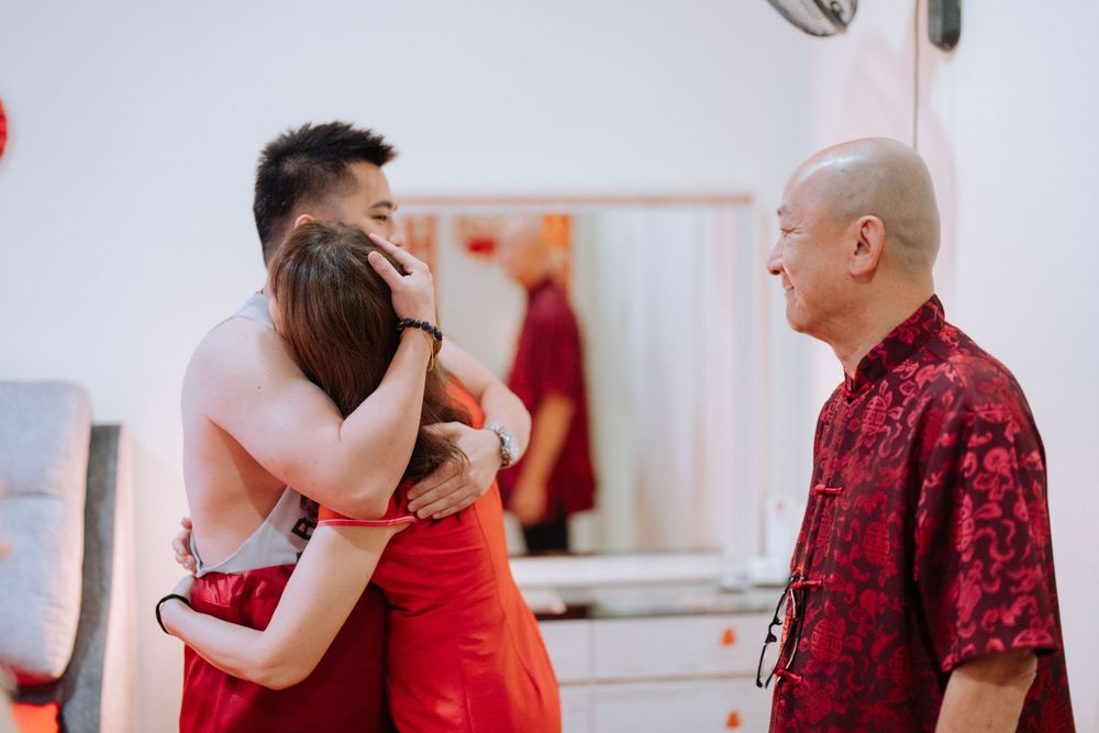 A joyful group embrace during a Chinese cultural celebration wearing red traditional attire.