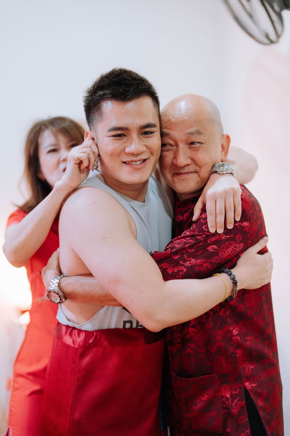 Warm family embrace during a Chinese cultural celebration with traditional red attire.