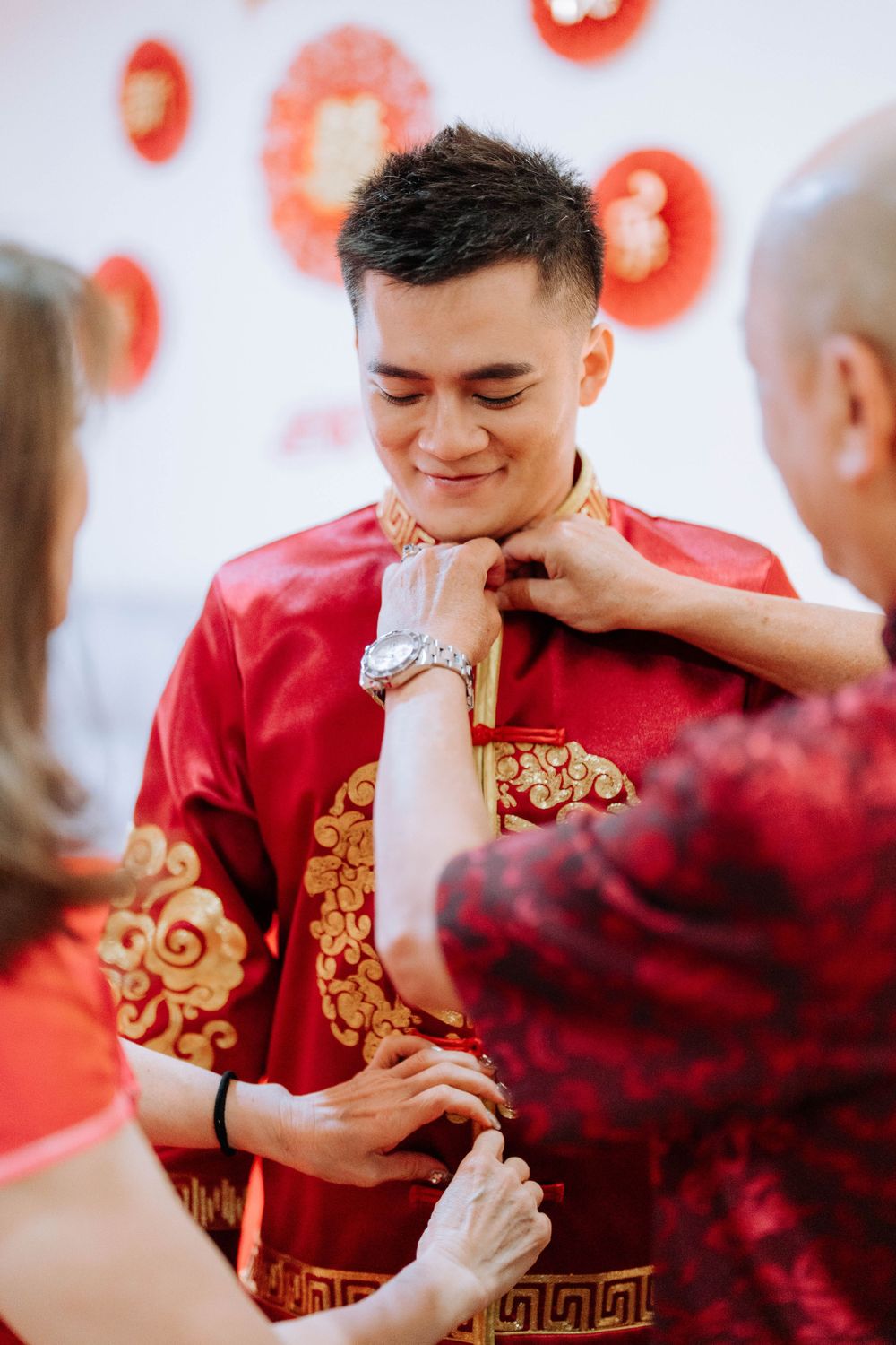 Adjusting traditional Chinese formal wear with gold embellishments during a ceremony.