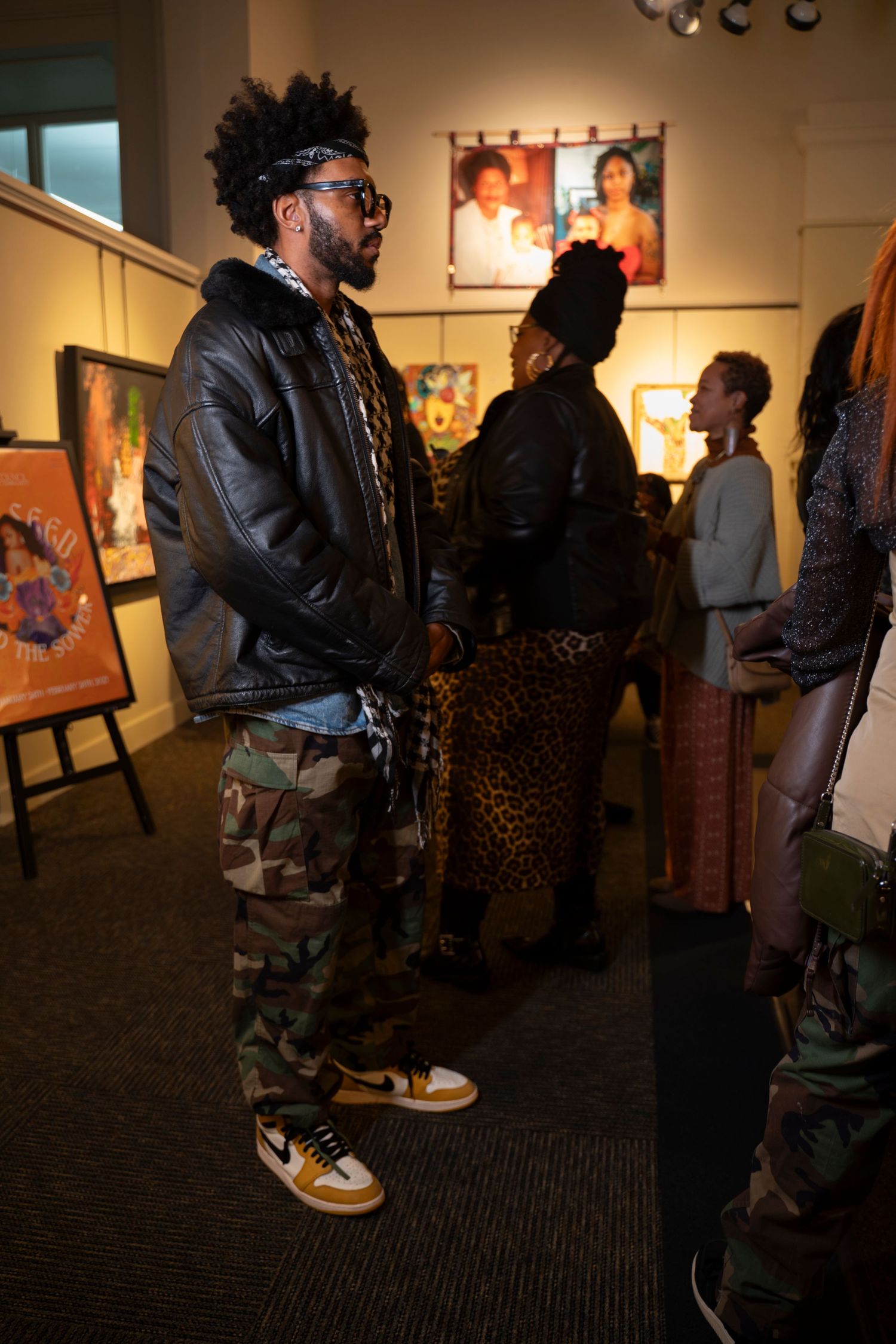 A gallery visitor in casual streetwear looks at art displays.