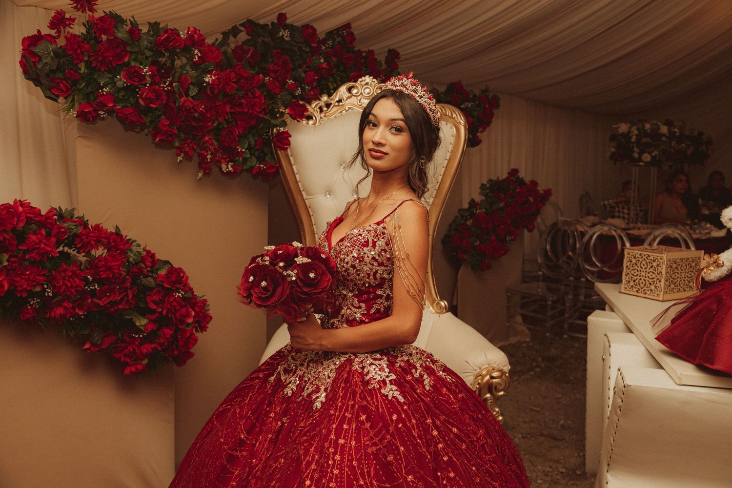A stunning red sequined ball gown sparkles in a romantic setting adorned with lush red rose decorations.