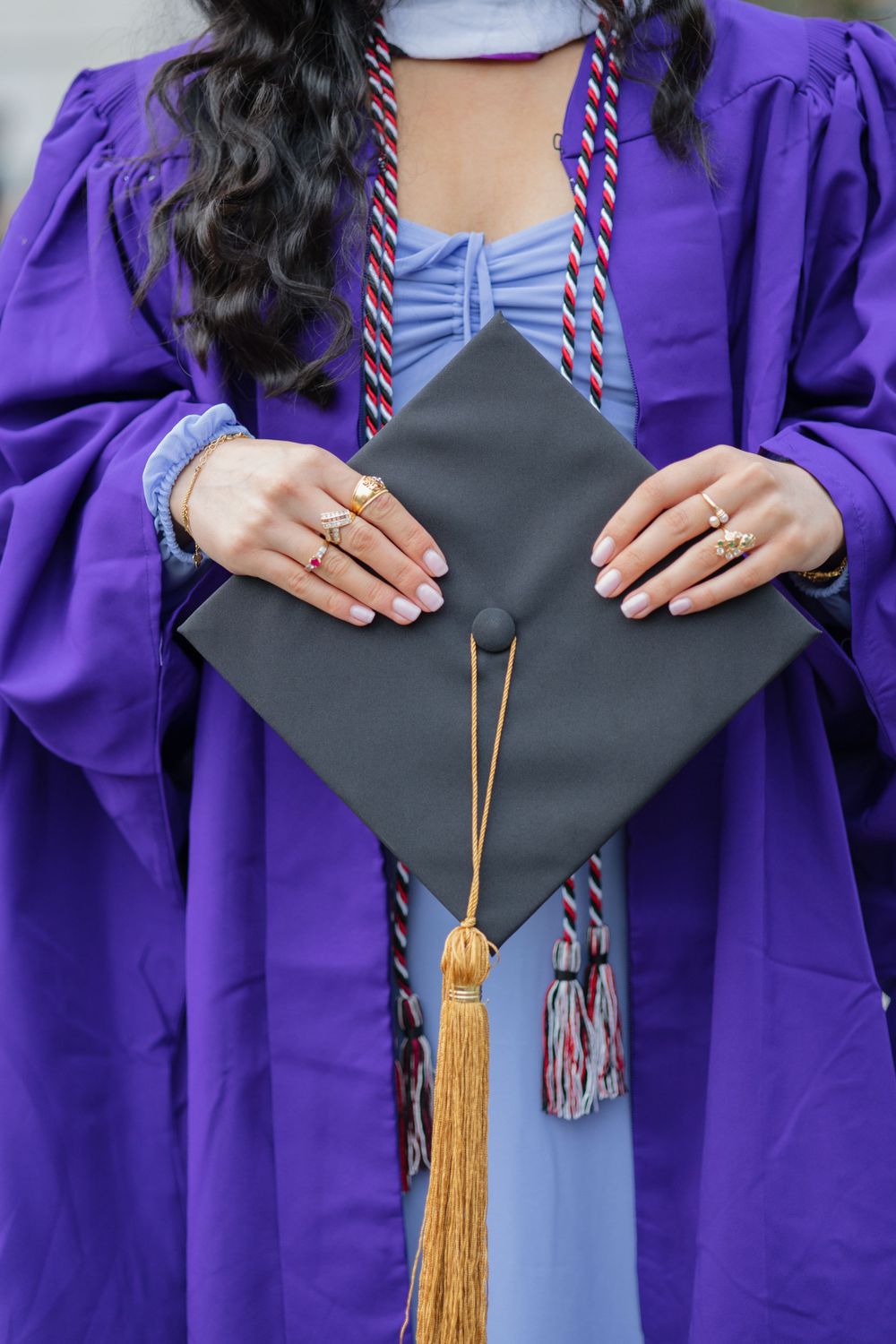 Close-up of graduation cap and purple gown with decorative bow detail.