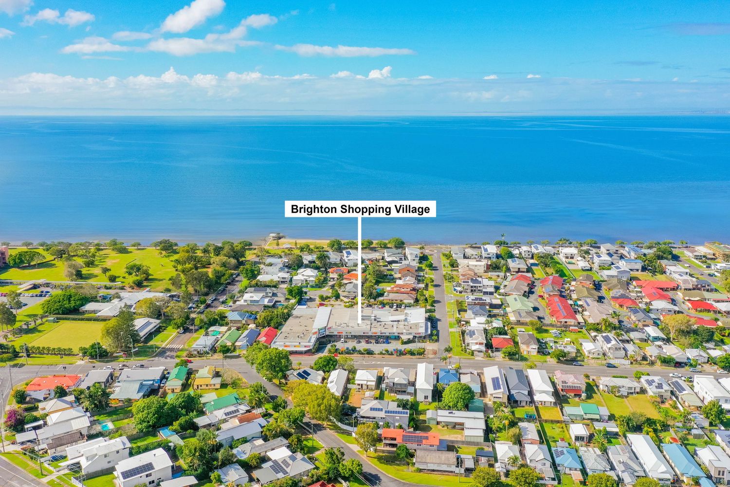 Aerial coastal view of Brighton suburb highlighting Brighton Shopping Village near the calm bay foreshore.