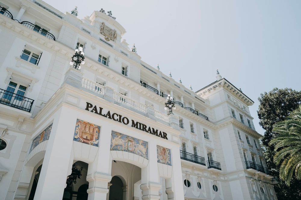 Exterior view of the white Palacio Miramar building with palm trees.