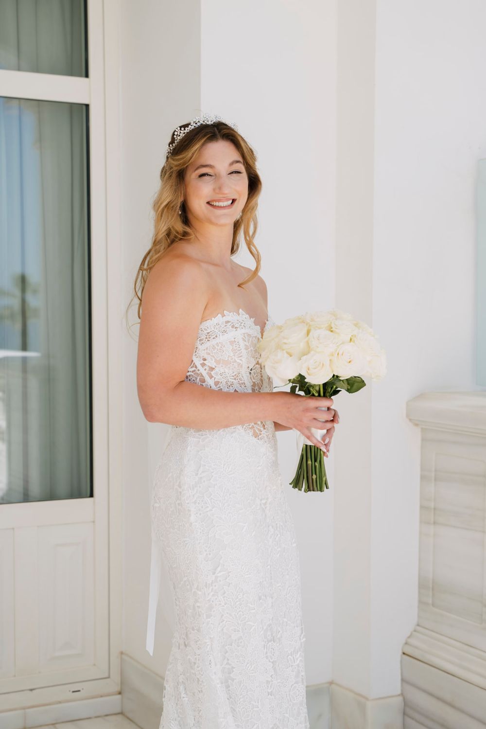Wedding dress with delicate lace details and a white rose bouquet.
