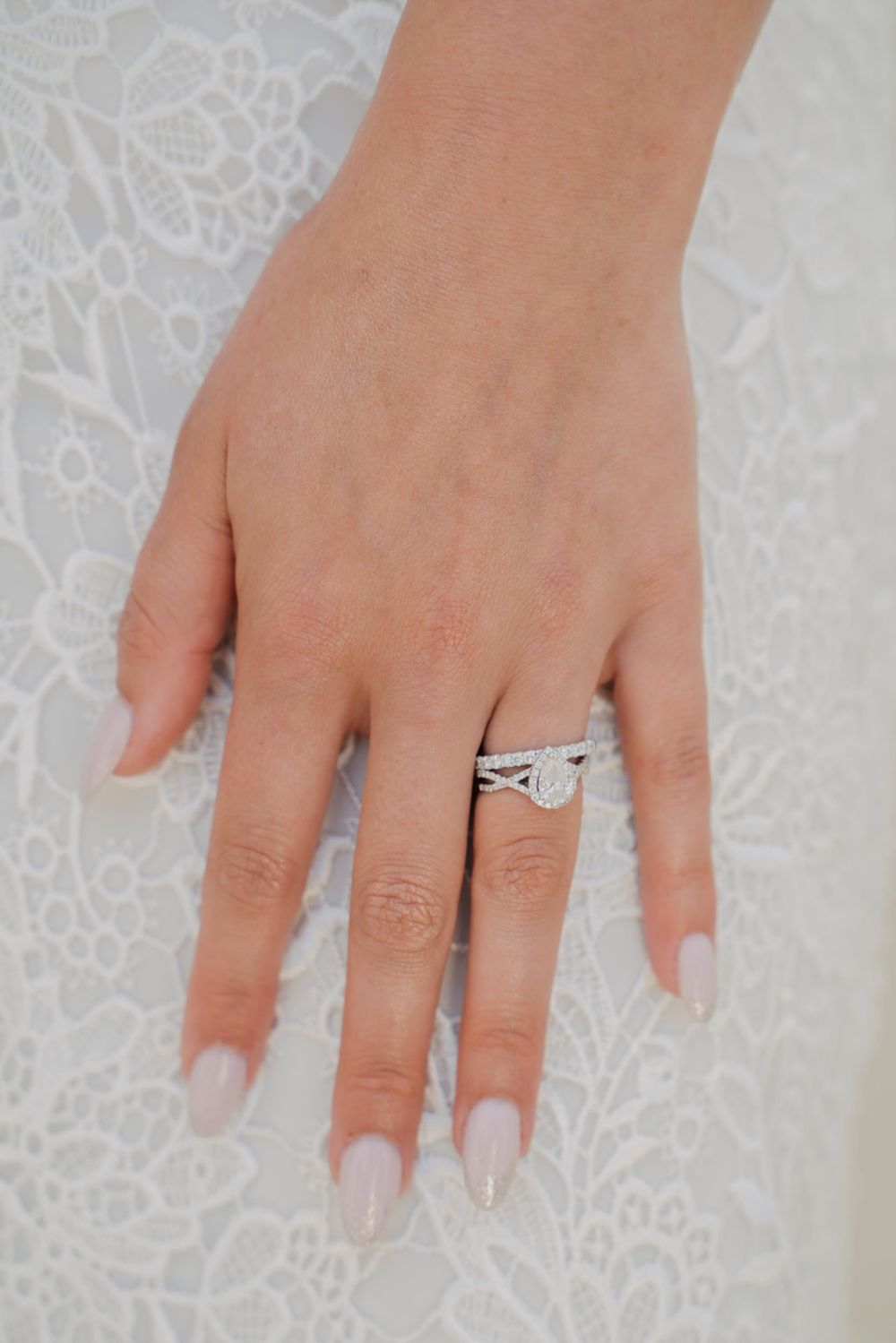 Close-up of a manicured hand wearing an elegant diamond wedding ring set.
